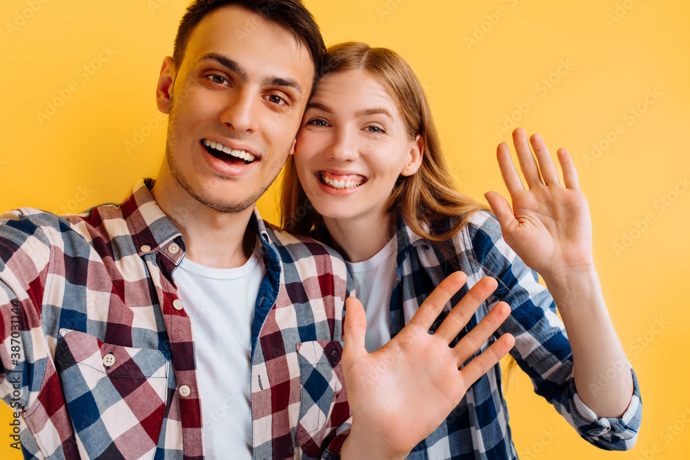 Young cheerful couple, man and woman make selfie on mobile phone on yellow background Young cheerful couple, man and woman make selfie on mobile phone on yellow background