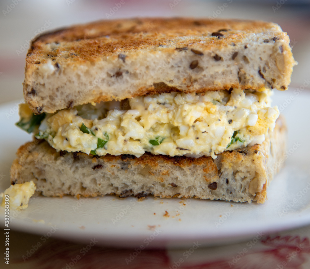 Half Egg Salad Sandwich made from Toasted Sourdough Whole Grain Bread on White Plate