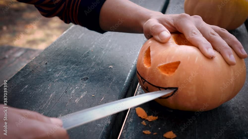 Slicing a smile on a scary Halloween pumpkin