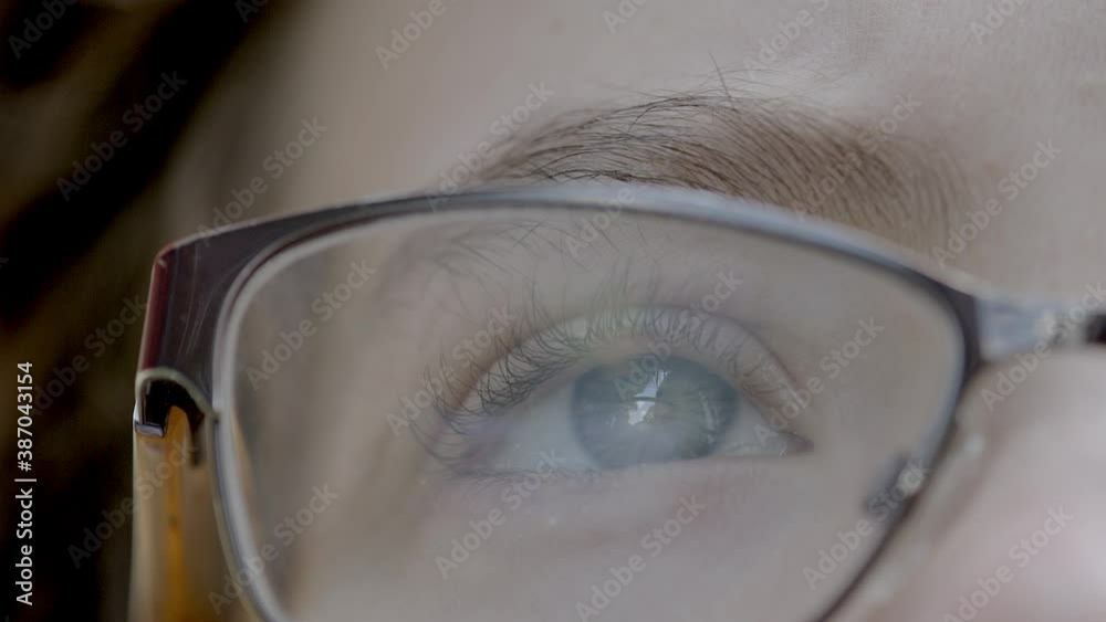 Closeup on pretty blue eye and eyelashes of a young boy wearing glasses as he gazes upward with rack focus