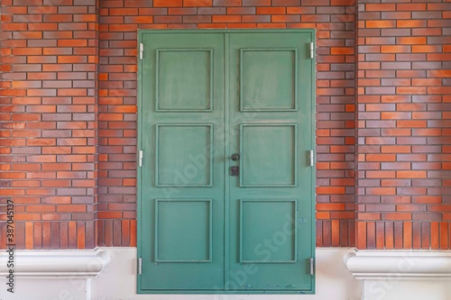 Antique green iron gate and red brick wall
