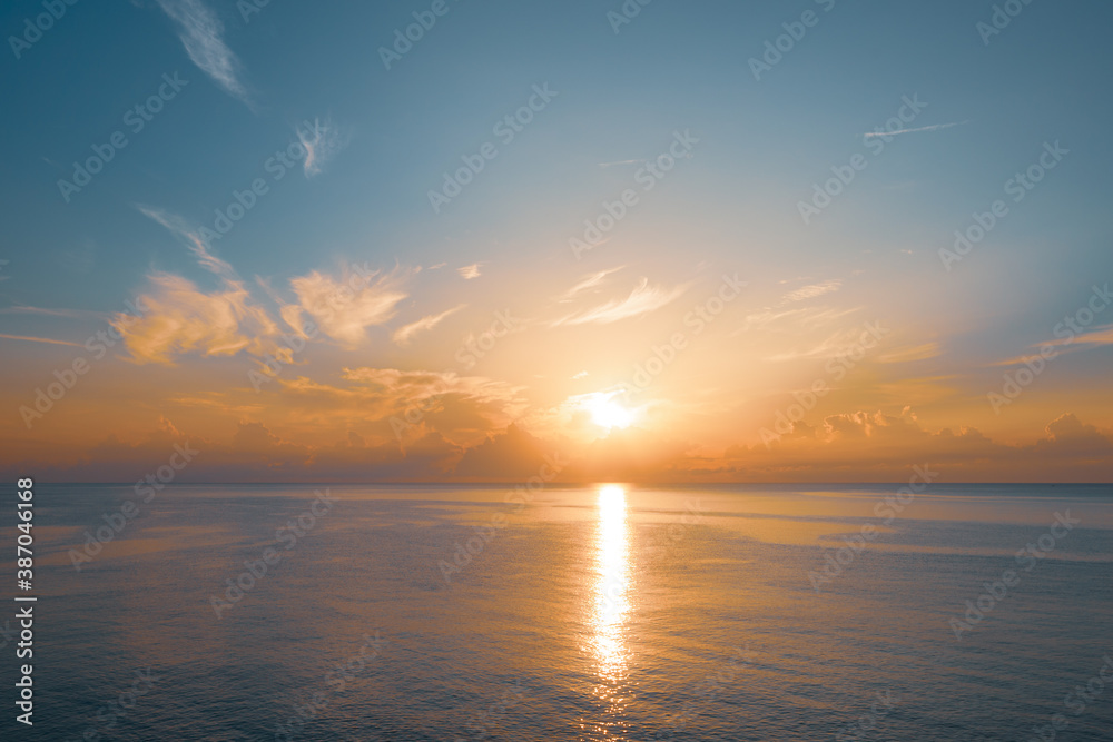 Sun rising from the sea. Colorful cloudy blue sky and sunbeams