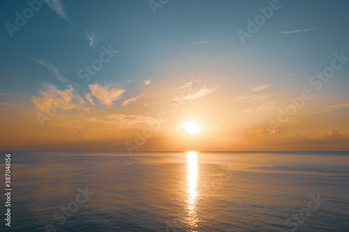 Sun rising from the sea. Colorful cloudy blue sky and sunbeams