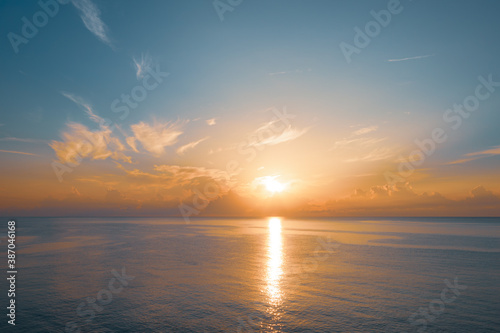 Sun rising from the sea. Colorful cloudy blue sky and sunbeams