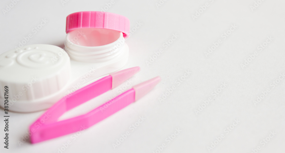 Contact lens, case and tweezers on gray background. Selective focus. Close up