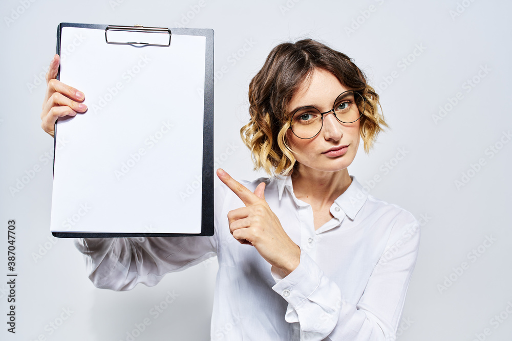 Business woman with a folder of white documents in her hand on a light background And hairstyle glasses model Business woman with a folder of white documents in her hand on a light background And hairstyle glasses model