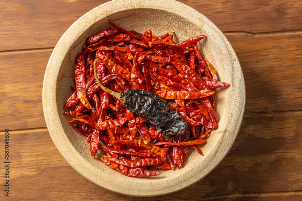 Tazón de madera con chiles secos y especias en detalle en mesa de madera Tazón de madera con chiles secos y especias en detalle en mesa de madera
