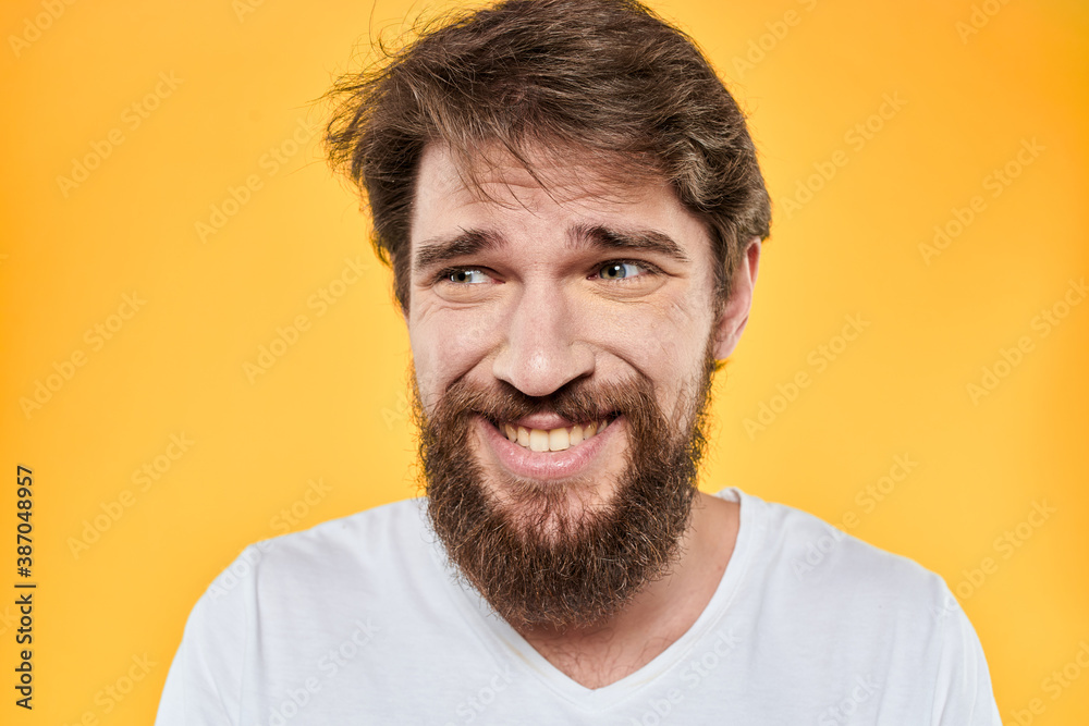 Man with emotional expression white t-shirt close-up studio yellow background Man with emotional expression white t-shirt close-up studio yellow background