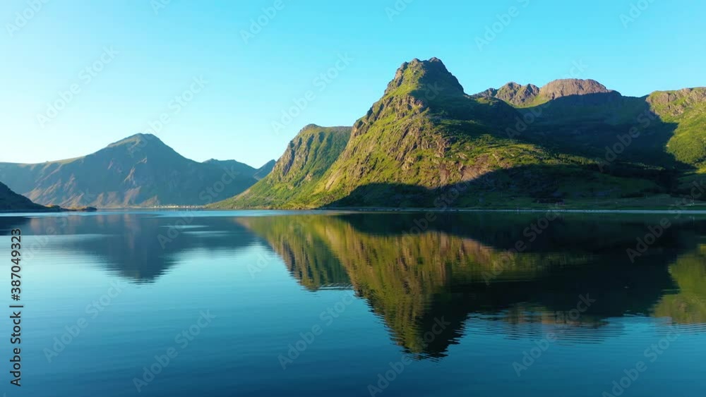 Aerial view low over a tranquil, mirroring ocean fjord, surrounded by mountains, in the Lofoten islands, Norway - dolly, drone shot - summer evening sunset Aerial view low over a tranquil, mirroring ocean fjord, surrounded by mountains, in the Lofoten islands, Norway - dolly, drone shot - summer evening sunset