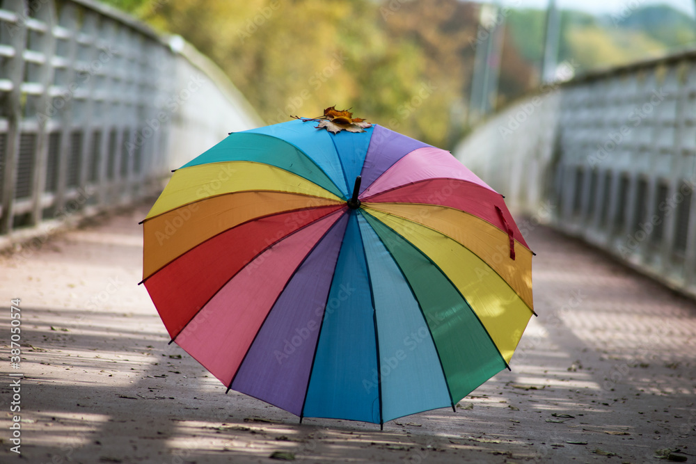 View of rainbow umbrella on the floor on modern bridge in autumn
