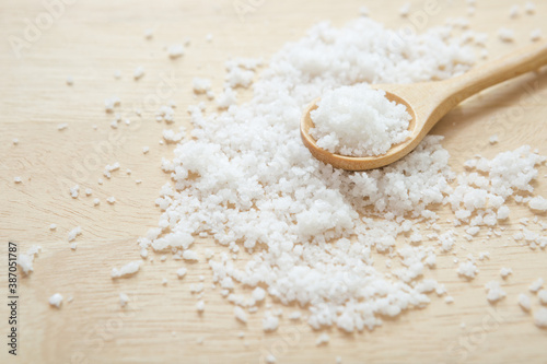 Salt in wooden spoon on the kitchen table and copy space