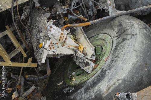 Plane wreckage, parts of the fuselage and landing gear with the wheel of the burned and broken aircraft at scrapyard of non-ferrous scrap metal for recycling.