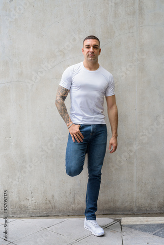 Full body shot of handsome man with tattoos leaning against wall © Ranta Images