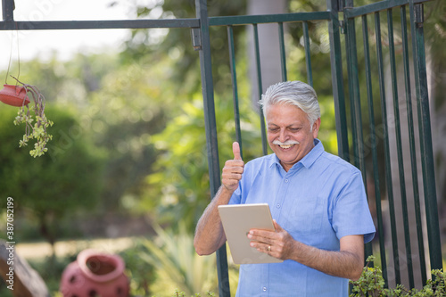 Photography Senior Man watching media content using digital tablet at park