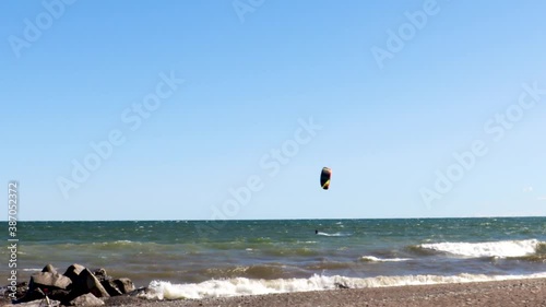 A lone kiteboarder skillfully traversing a rocky shoreline, on a beautify, virtually cloudless day. photo