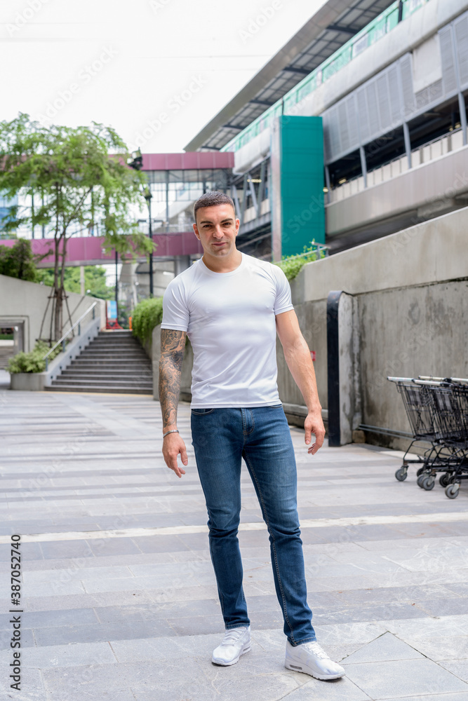 Full body shot of handsome man with tattoos in the city