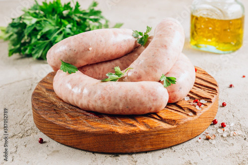 Obraz na plátně Raw chicken sausage for grilled on wooden cutting board with parsley