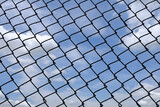 Blocking freedom concept. the bright sky behind the pattern of the metal fence.