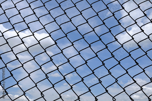 Blocking freedom concept. the bright sky behind the pattern of the metal fence.