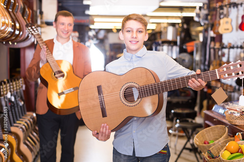 Man and a boy show branded acoustic guitars in a music store