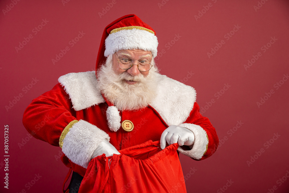 Naklejka premium Santa Claus surprised looking inside the gift bag. Christmas is coming. Merry Christmas.