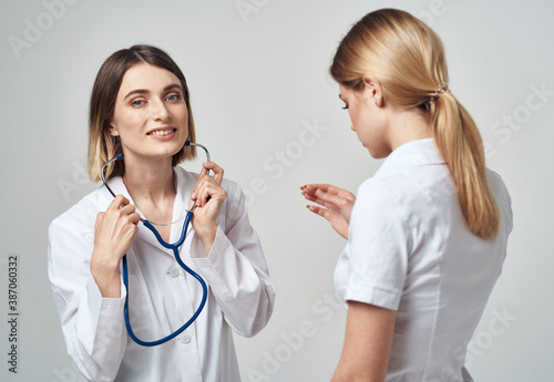 A nurse with a stethoscope and a patient on a light background