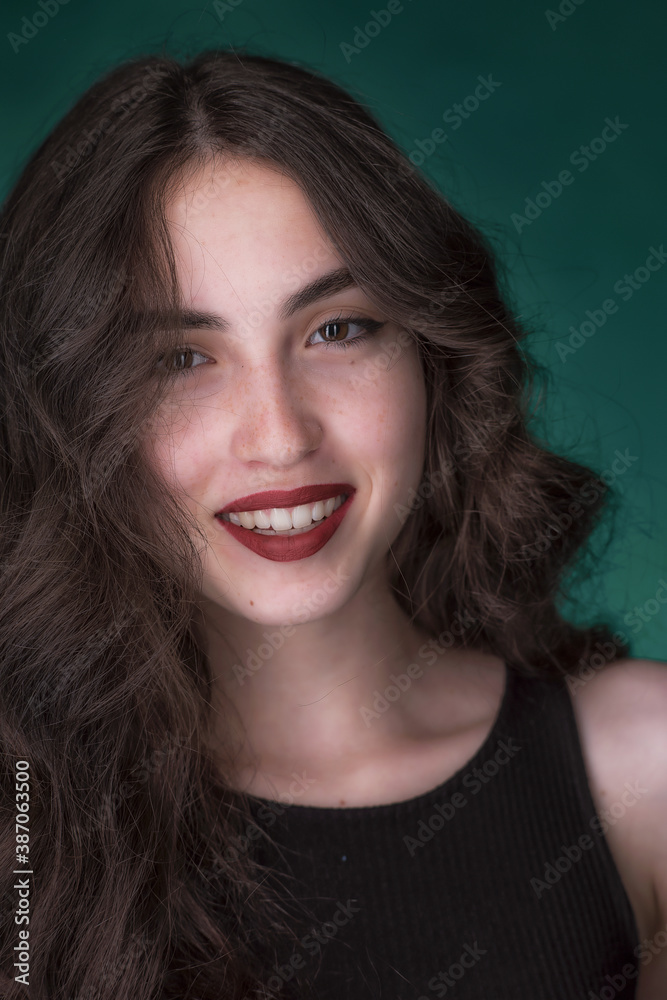 Portrait of a young brunette with lush wavy hair and beautiful highlights in the eyes Portrait of a young brunette with lush wavy hair and beautiful highlights in the eyes