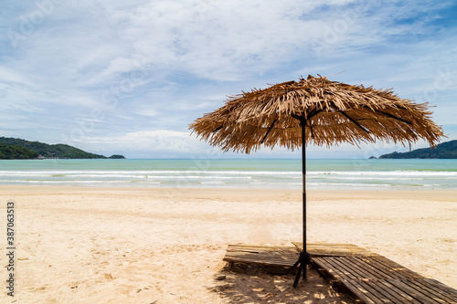 Beach umbrella made of palm leafs on a perfect white beach in front of sea in at Patong Beach  Phuket  Thailand