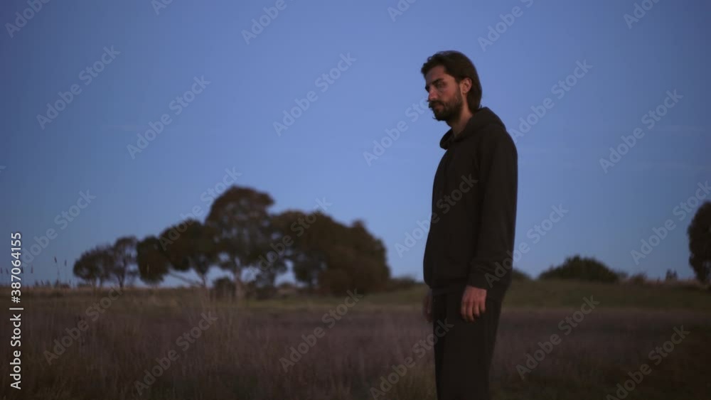 absent minded man standing alone in wide calm field, autumn, middle shot absent minded man standing alone in wide calm field, autumn, middle shot