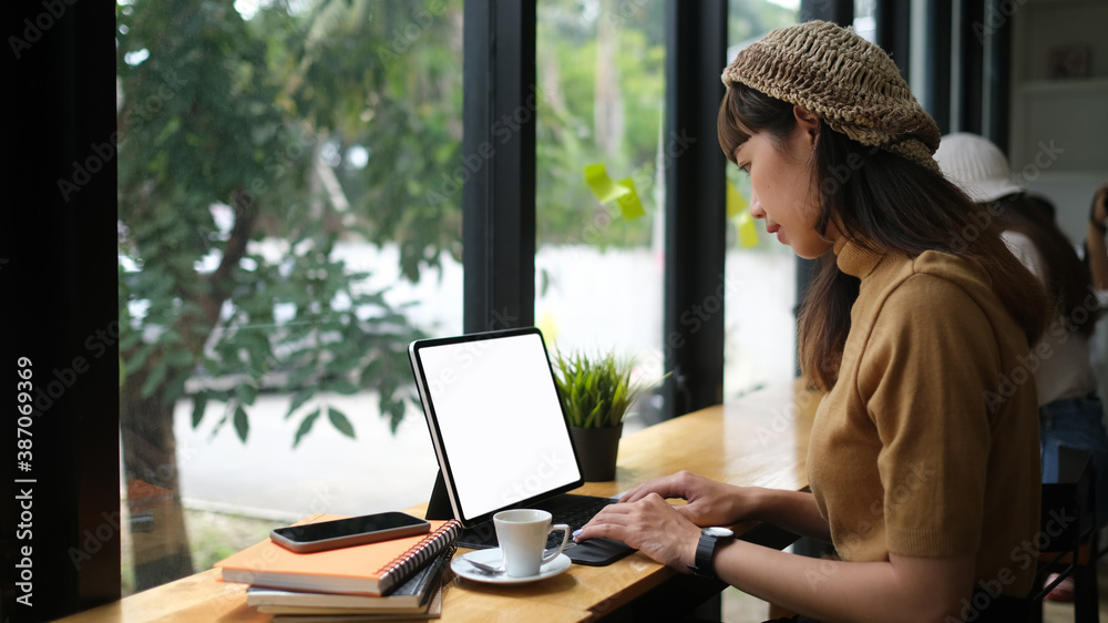 Side view of young female free lancer working on digital tablet while sitting in meeting room. Side view of young female free lancer working on digital tablet while sitting in meeting room.