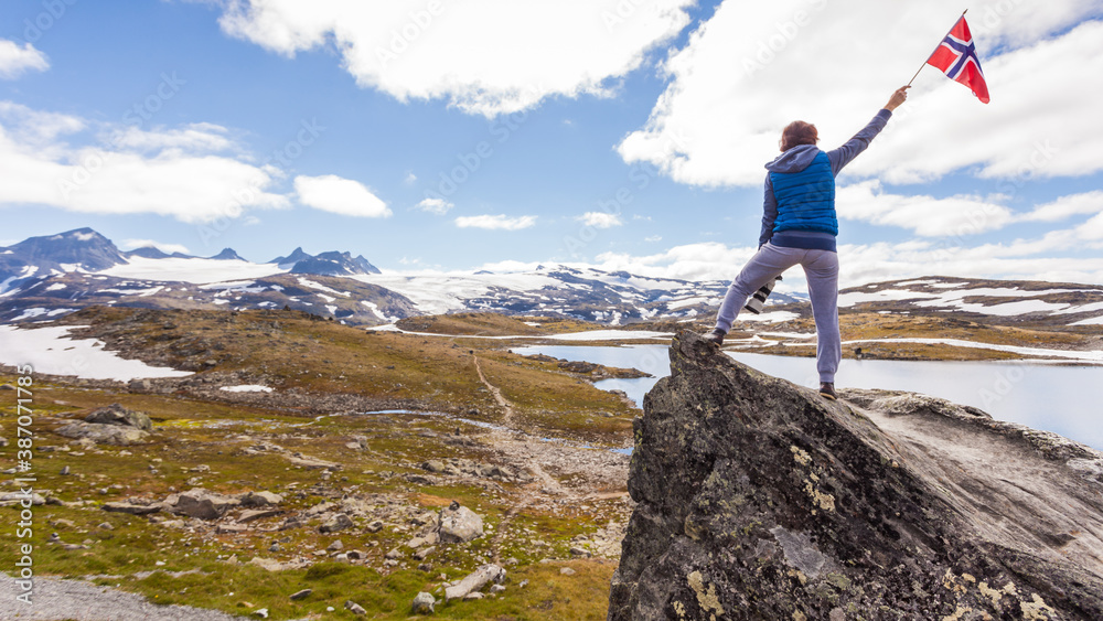 Obraz premium Tourist with camera and flag in Norway mountains