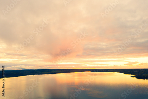 Aerial view sunset over the forest and lake. View from drone. Aerial view cloudscape. Texture of clouds. View from above. © Aleksei