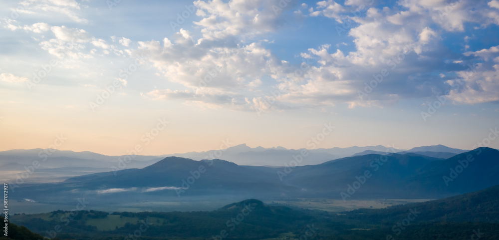 Early morning in the mountains. Morning sun and haze in the valley against the background of mountains.