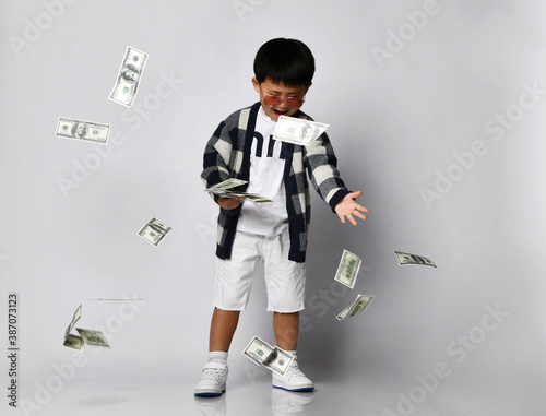Fotografie Happy screaming asian rich kid boy millionaire stands with bunch of moneys dolla