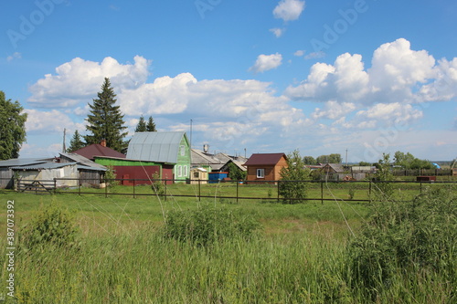 old houses in the village in the summer on the green grass behind the fence