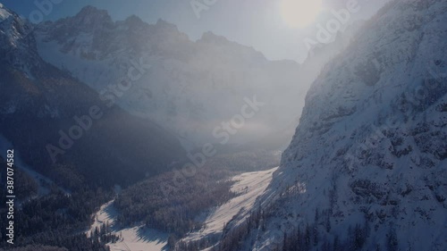 Revealing drone shot of a snowy mountains and valley on a beautiful sunny winter day.