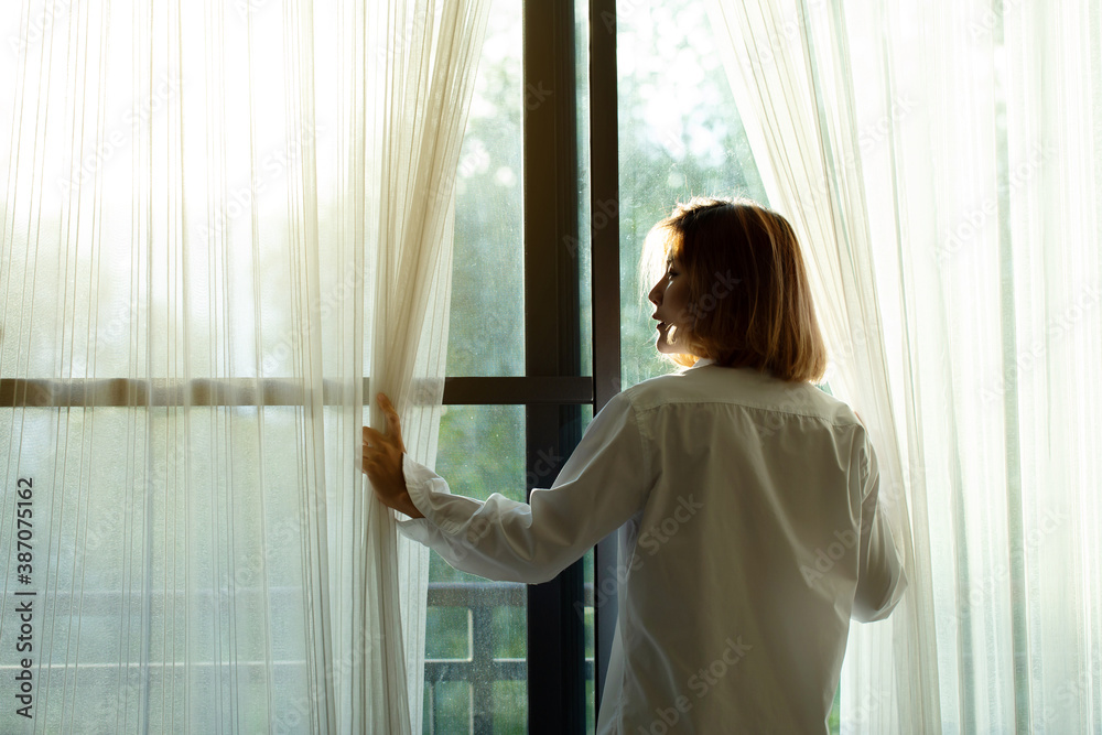 happy woman wake up and open the curtains in the morning to get fresh air and get the morning sun.
