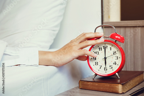 Woman hand turning off alarm clock waking up at morning