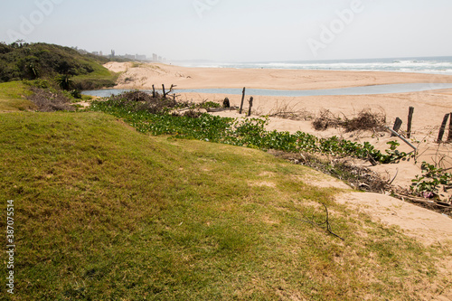 River Running into Sea Between Grass and Vegetation Covered Dunes