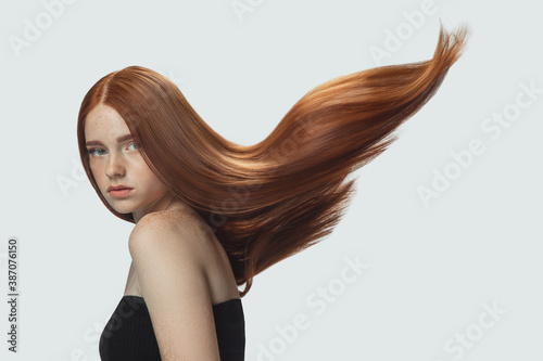 Wallpaper Mural Beautiful model with long smooth, flying red hair isolated on white studio background
