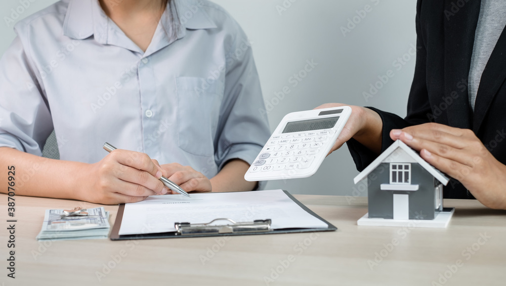 Fototapeta premium A real estate agent with a home model is talking to clients about renting a house and buying home insurance and contracting the contract after the formal negotiation is completed