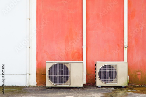 Outdoor condensing unit of an air conditioner with its copper pipes covered with white decorative PVC duct. photo