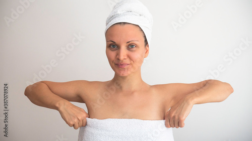 Caucasian woman pulls up the towel in which she is wrapped.