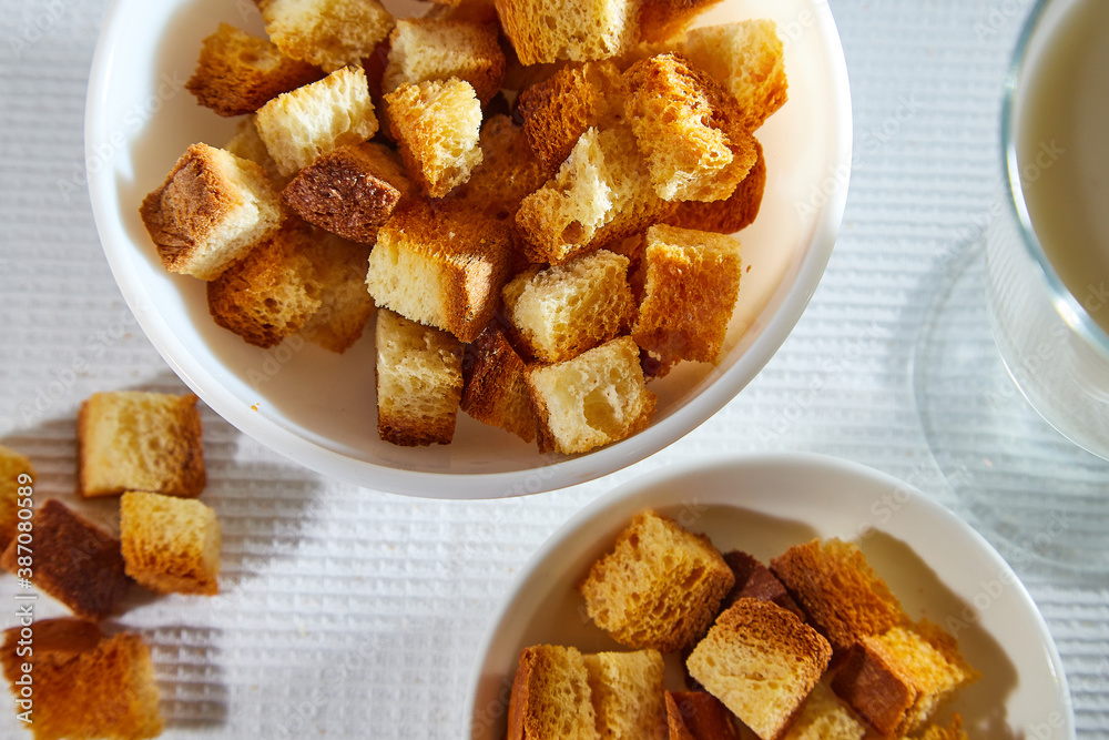 Square toasted pieces of homemade delicious rusk, hardtack, Dryasdust, zwieback in a plate on a white tablecloth. Square toasted pieces of homemade delicious rusk, hardtack, Dryasdust, zwieback in a plate on a white tablecloth.