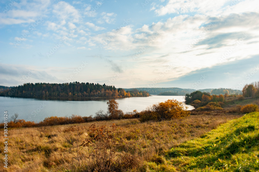 Autumn landscape. A lake with hilly shores and autumn orange forest. 