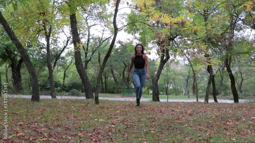 Beautiful girl running in slow motion in a park. Young female in a forest with tall trees. Beautiful girl running in slow motion in a park. Young female in a forest with tall trees.