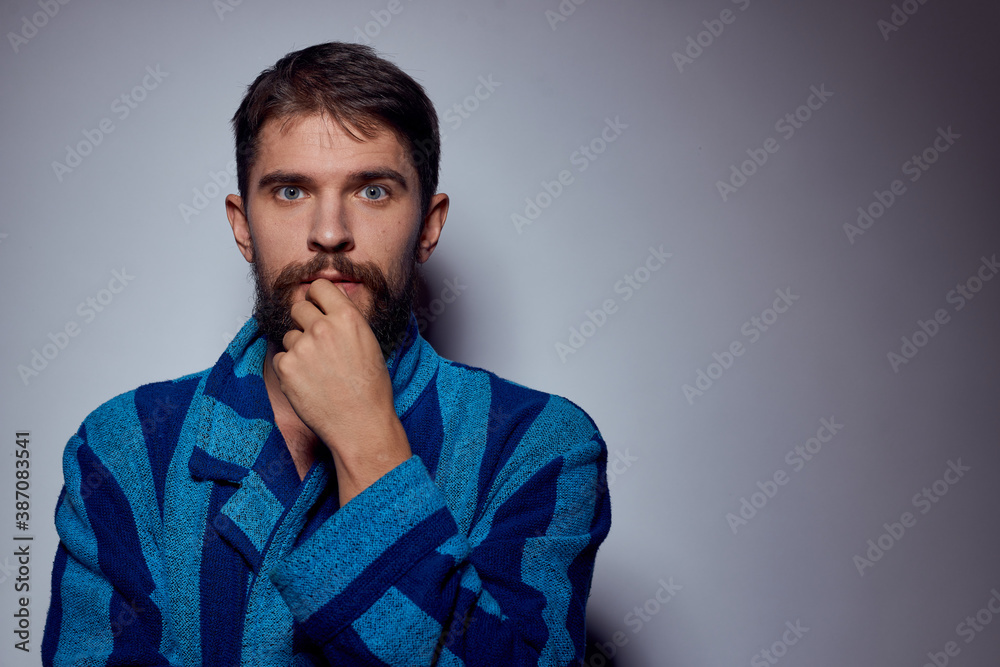 emotional man in a blue striped robe with a belt on a light background cropped view close-up emotional man in a blue striped robe with a belt on a light background cropped view close-up