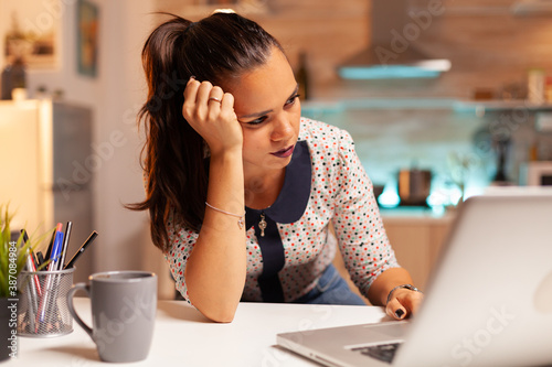 Woman having a headache while trying to finish a project before deadline. Employee using modern technology at midnight doing overtime for job, business, busy, career, network, lifestyle ,wireless. photo