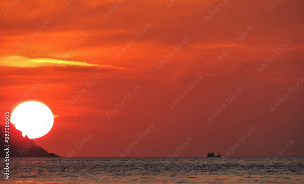 In the evening, sunset, round sun large, shining orange, beautiful yellow reflecting the sea surface in gold,  boat black silhouette