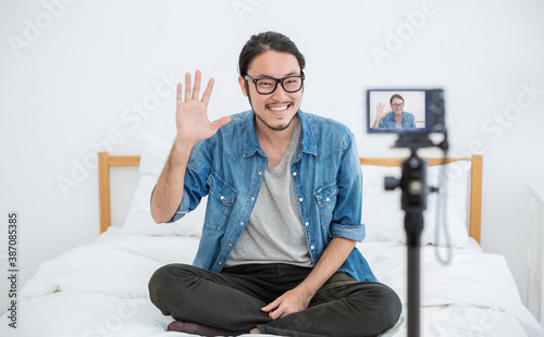 Portrait of small business owner sme vlogger man, video online marketing live in camera. Young asian guy say hi to social network. SME entrepreneur blogger online business concept photo